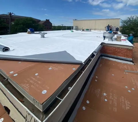 Commercial roofing project, workers laying tarps